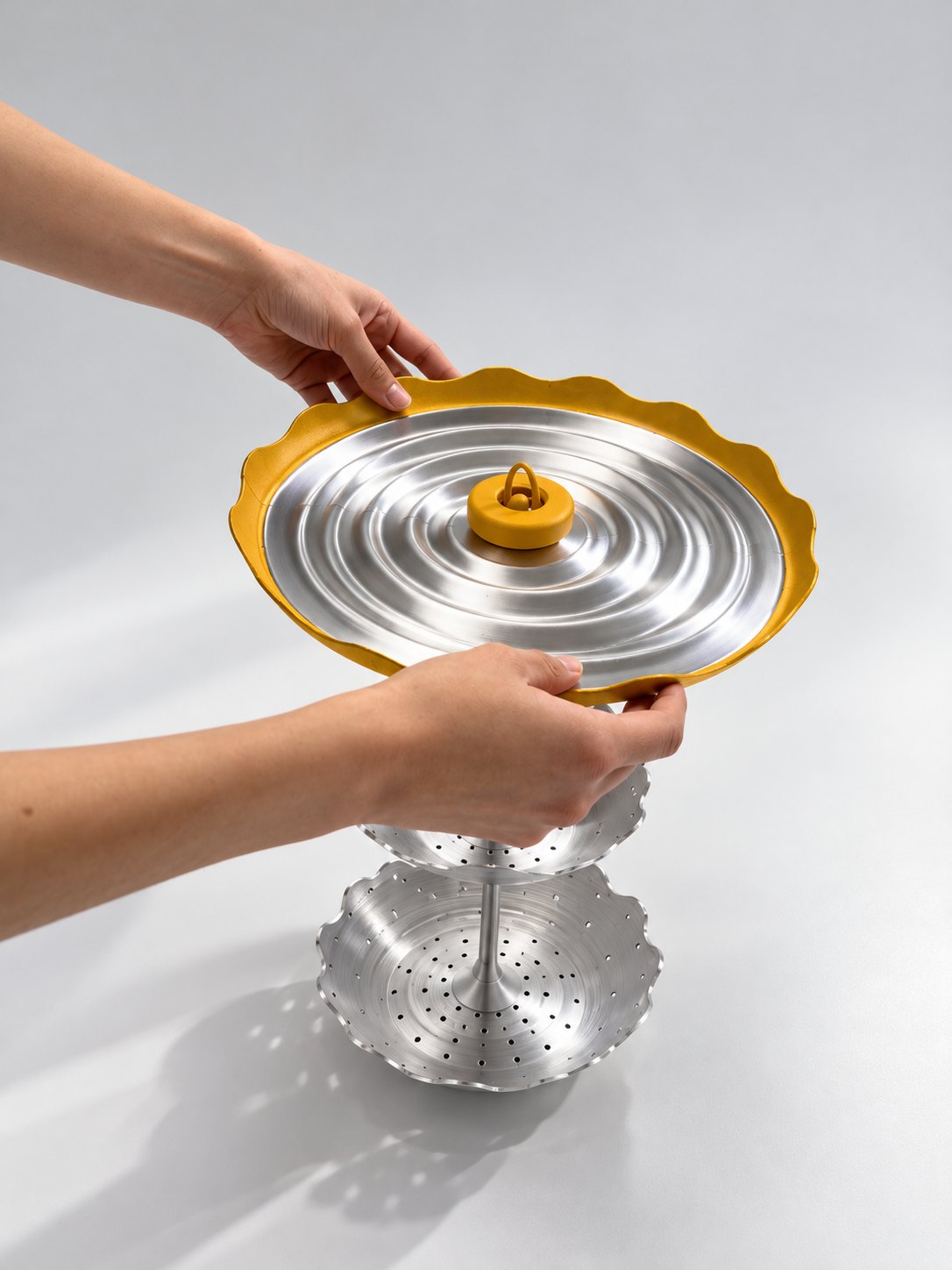 Two hands setting the “Skirt” lid onto the tower