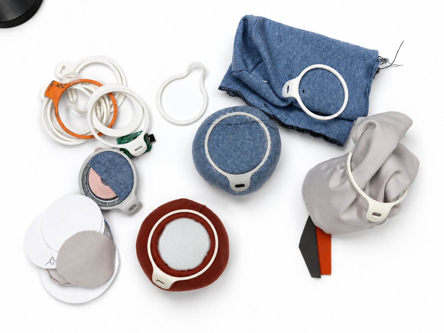 Prototypes laid out: printed rings, knit and fabric skins, a charging coil and paper templates